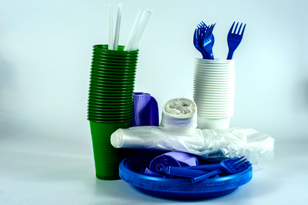 The bright plastic tableware and rolls with polythene packaging on light grey backgroundの写真素材