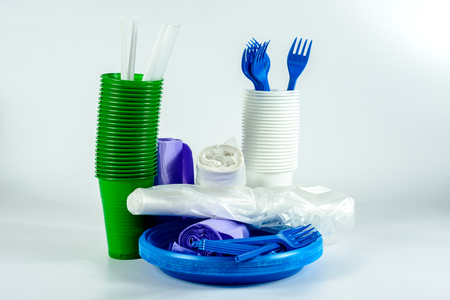 The bright plastic tableware and rolls with polythene packaging on light grey backgroundの写真素材