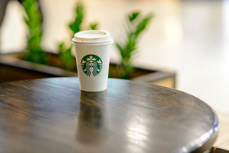 A white paper cup with coffee from Starbucks against the background of the blurry lights of the shopping center.  Russian Federation, Rostov-on-Don, April 13のeditorial素材