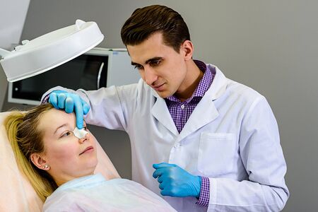 Male doctor preparing a mold of the curve of the nose the patient is female, to follow the alignment...