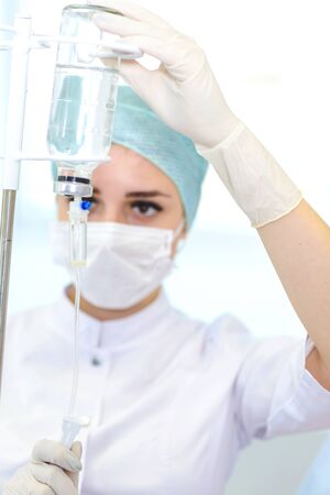 The medical worker adjusts the dropper to stimulate the patientの写真素材