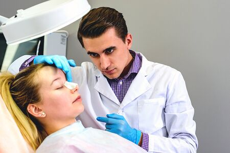 Male doctor preparing a mold of the curve of the nose the patient is female, to follow the alignment procedure of the nose. Rena Therme Hartman for plastic surgery.の写真素材