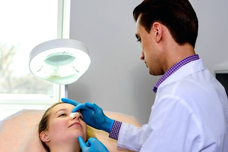 Male doctor preparing a mold of the curve of the nose the patient is female, to follow the alignment procedure of the nose. Rena Therme Hartman for plastic surgery.の写真素材
