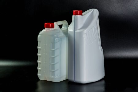Plastic cans and containers for liquids white color, used with red covers on a black backgroundの写真素材