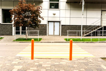 Yellow-and-white pedestrian crosswalk across the roadway with restriction posts for non-traffic vehicles.の写真素材