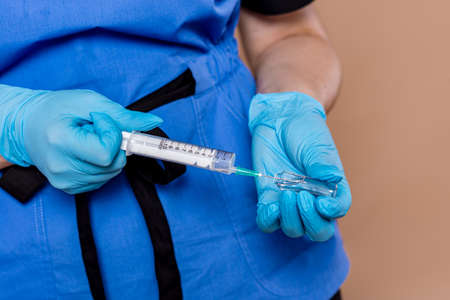 Woman in medical workwear with bottle and ampule with medicines in hands. Isolated on white background. Focus on hands.の写真素材