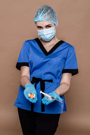 Woman in medical workwear with bottle and ampule with medicines in hands. Isolated on white background. Focus on hands.の写真素材