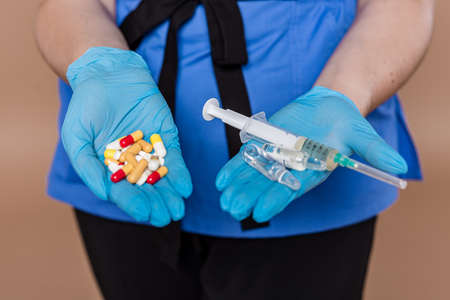 Woman in medical workwear with bottle and ampule with medicines in hands. Isolated on white background. Focus on hands.の写真素材
