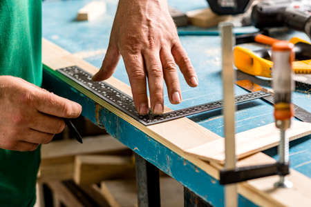 Carpenter's hands. Men's hands that hold a pencil and ruler for marking parts before productionの写真素材
