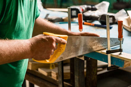Carpenter working on wood craft using saw and ruler tools for hand crafting at workshop to produce construction material or wooden furnitureの写真素材