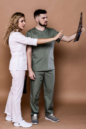 Young doctors on a plain background in medical clothing. They discuss brain imaging data together.の写真素材