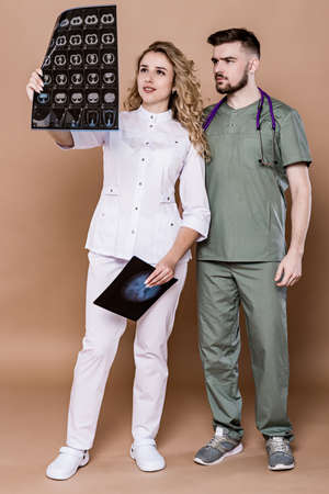 Young doctors on a plain background in medical clothing. They discuss brain imaging data together.の写真素材