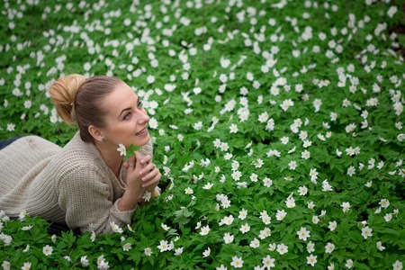 Sunlit forest. Beautiful sensual lady lying on flower meadow