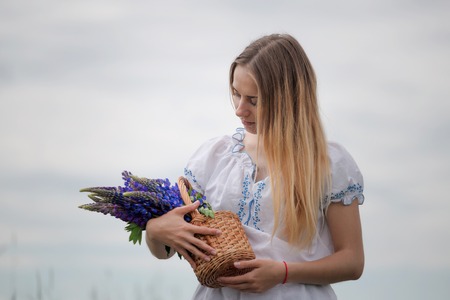 Portrait of beautiful young woman with flowers in the field.