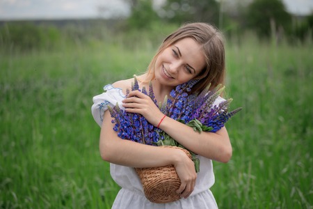 Portrait of beautiful young woman with flowers in the field.の写真素材