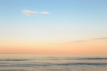 Still blue sea water under colorful evening cloudy sky.の写真素材