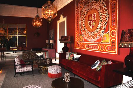Old classical spanish interior with big red velvet sofa, different chairs and carpet on the wallのeditorial素材