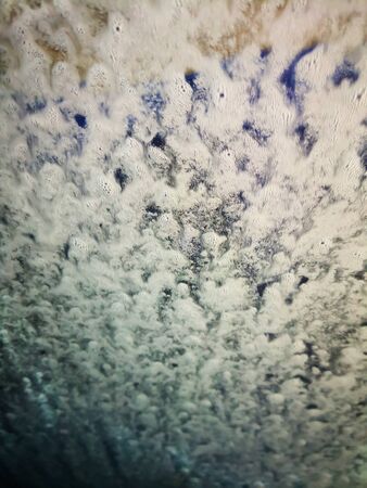 Waves of the white foam on the windowwith blue and brown background. Imitation of cloudy skyの写真素材