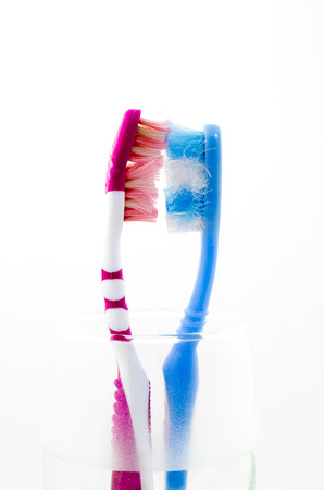two old used colorful toothbrushes in a glassの写真素材