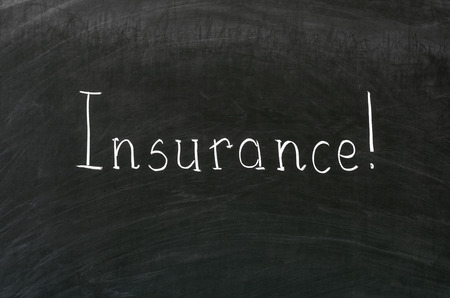 Insurance word handwritten with white chalk on a blackboardの写真素材