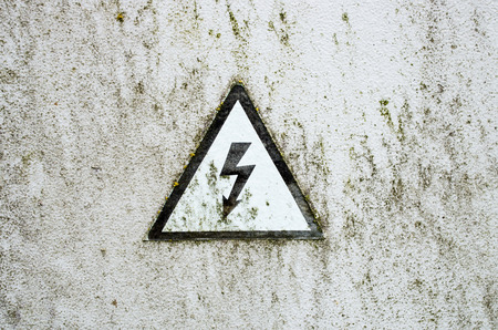 The old high voltage sign on white metal plateの写真素材