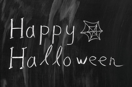 Happy Halloween writed with white chalk on a blackboard.の写真素材