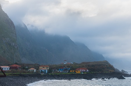 Several houses at the shore of ocean. Opposite side of houses the big mountain.のeditorial素材