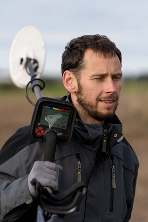 A man is looking for metal with a metal detector.