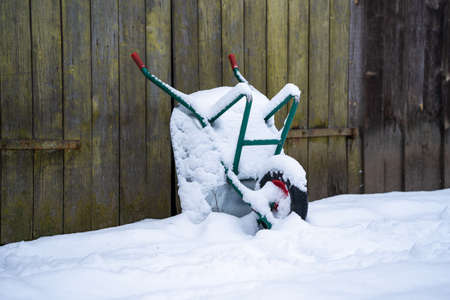 Wheelbarrow at a wall in snow at winter time.の写真素材