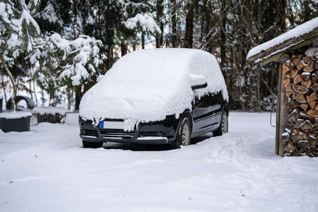 A car under a snow drift. Heavily snow-covered car in the yard.の写真素材