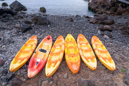Several colorful kayak lifted on the shore between rocks in Madeira island.の写真素材