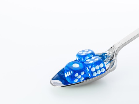 three blue dices in metall spoon on white backgroundの写真素材