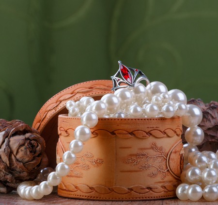 small birch bark casket with pearl beads on green fabric backgroundの写真素材
