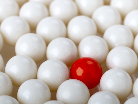 stand out red ball surrounded by white ballsの写真素材