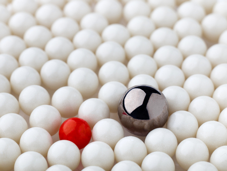 stand out red and metal balls surrounded by white ballsの写真素材