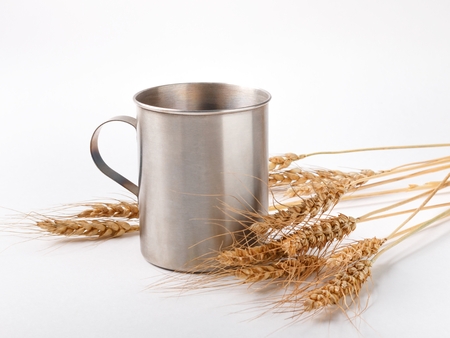 wheat spikelets and metal mug on white backgroundの写真素材