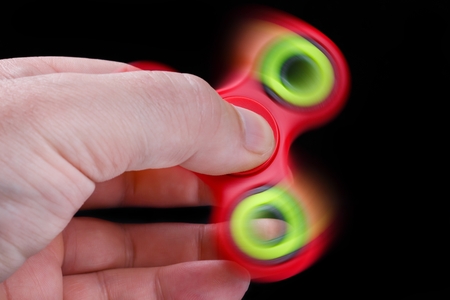 Man hand holding fidget spinner on black backgroundの写真素材
