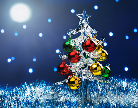 Glass christmas tree with colorful balls on blurred lights backgroundの写真素材