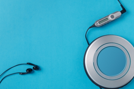 personal cd player with remote control and portable audio earphones on blue backgroundの写真素材