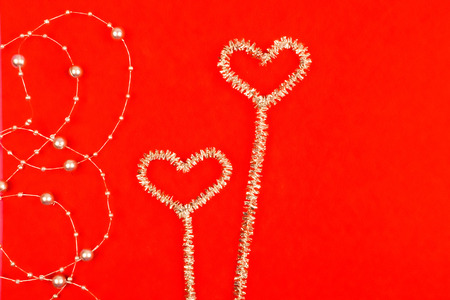 Noctilucent hearts with beads on a red background.の写真素材