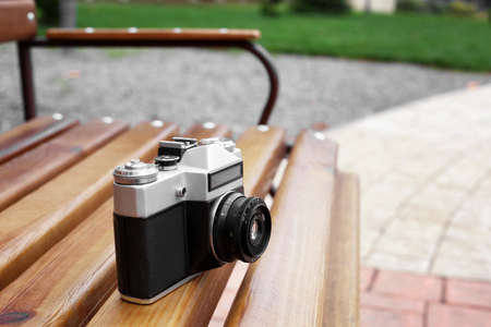 old retro camera on a wooden bench on the street.