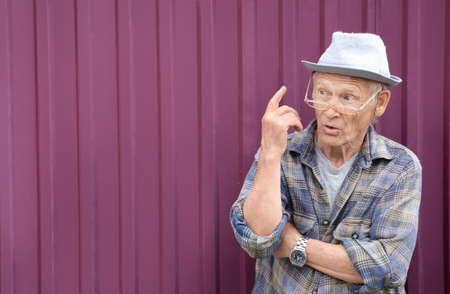 An elderly gray-haired man in glasses came up with something. Brilliant ideas. old man and thoughtの写真素材