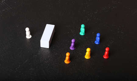 Multi-colored little men on a black background. The man behind the wall. Social distance and misunderstanding in the team.の写真素材
