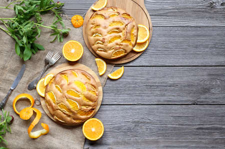 Sunny Orange Cake flavored with freshly squeezed orange juice and orange zest with candied orange on top. Citrus pastries on a wooden background with fresh juicy orangesの写真素材