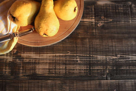 Real natural pears on a dark background with sunlight. fruit pear on a boardの写真素材