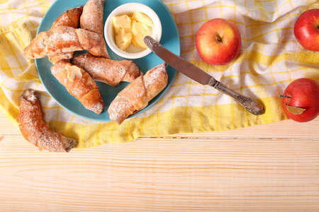 Breakfast set with plase for text. Freshly baked bagels close-up with a glass of juice and butter on a rustic wooden surface and a blue background. Breakfast and good morning.の写真素材
