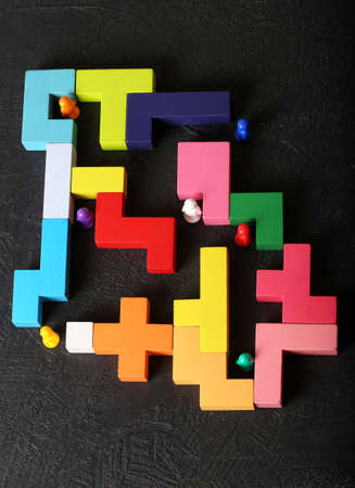 Multi-colored people in a multi-colored maze on a dark background close-up. mancell. The concept of...