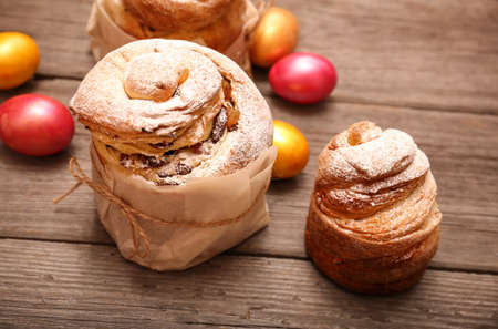 Closeup of homemade easter kraffins with raisins and icing sugar on a cutting board, with easter eggs.Homemade holiday cakes kulich kraffin.の写真素材