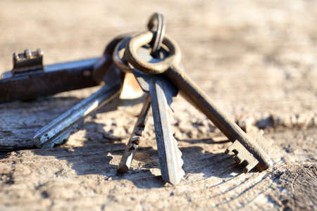 Bunch of keys close up. Vintage rusty different keys on a weathered wooden background. Concept of many wrong options.の写真素材