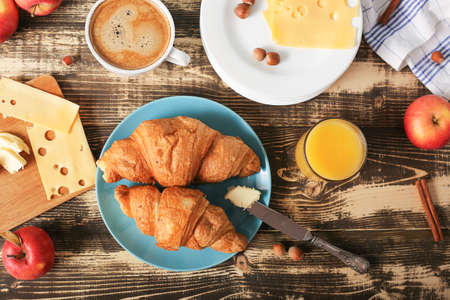 Breakfast set top view. Freshly baked croissants close-up with a cup of coffee, a glass of juice and cheese on a rustic wooden surface. French breakfast and good morning.の写真素材